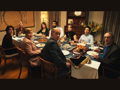 A Jewish family gathers around a Shabbat dinner table, all turning to look at the camera in surprise or tension.